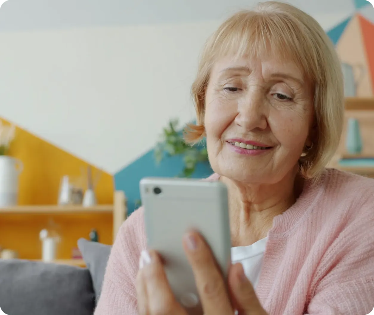 Smiling older woman using her phone at home